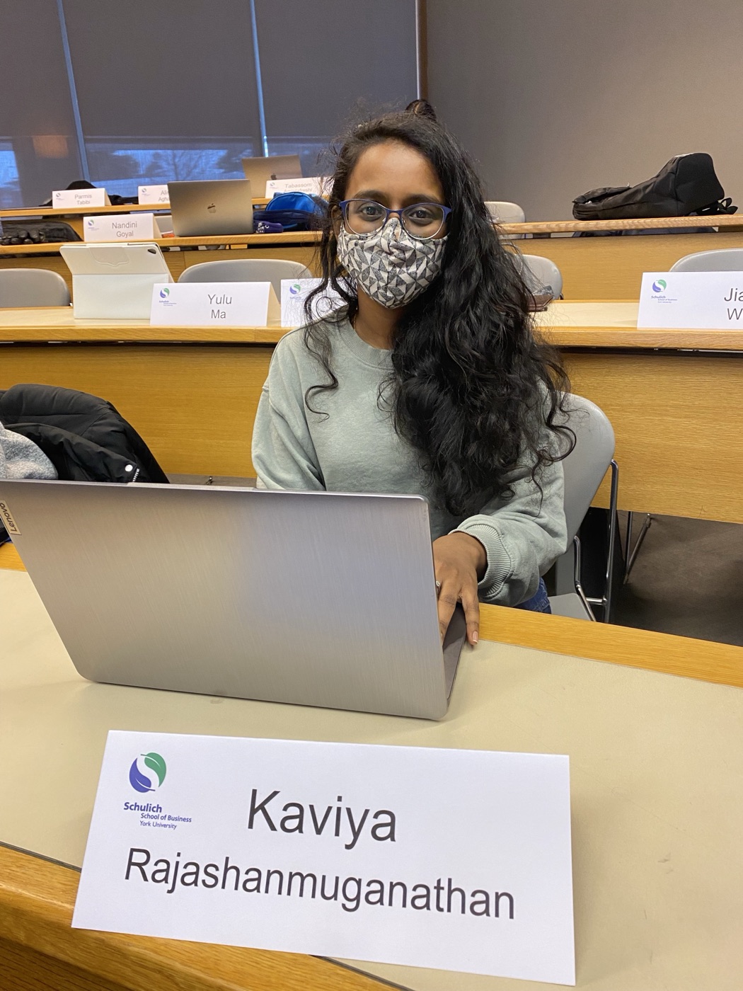 Kaviya seated in class with a name card reading Kaviya Rajashanmuganathan, Schulich School of Business